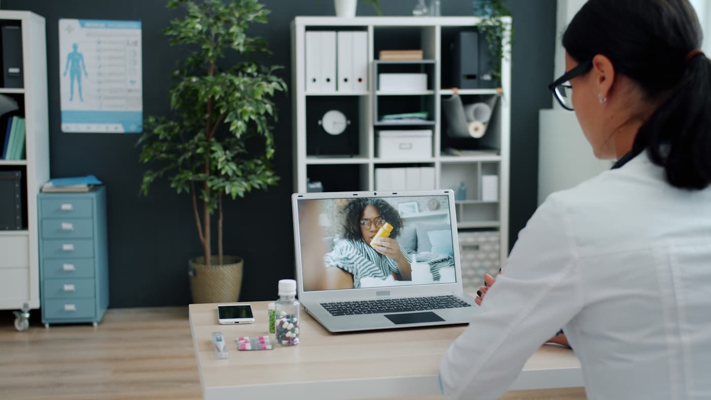 Médica atendiendo una consulta por videollamada en una clínica, imagen realista para diseño web sanitario